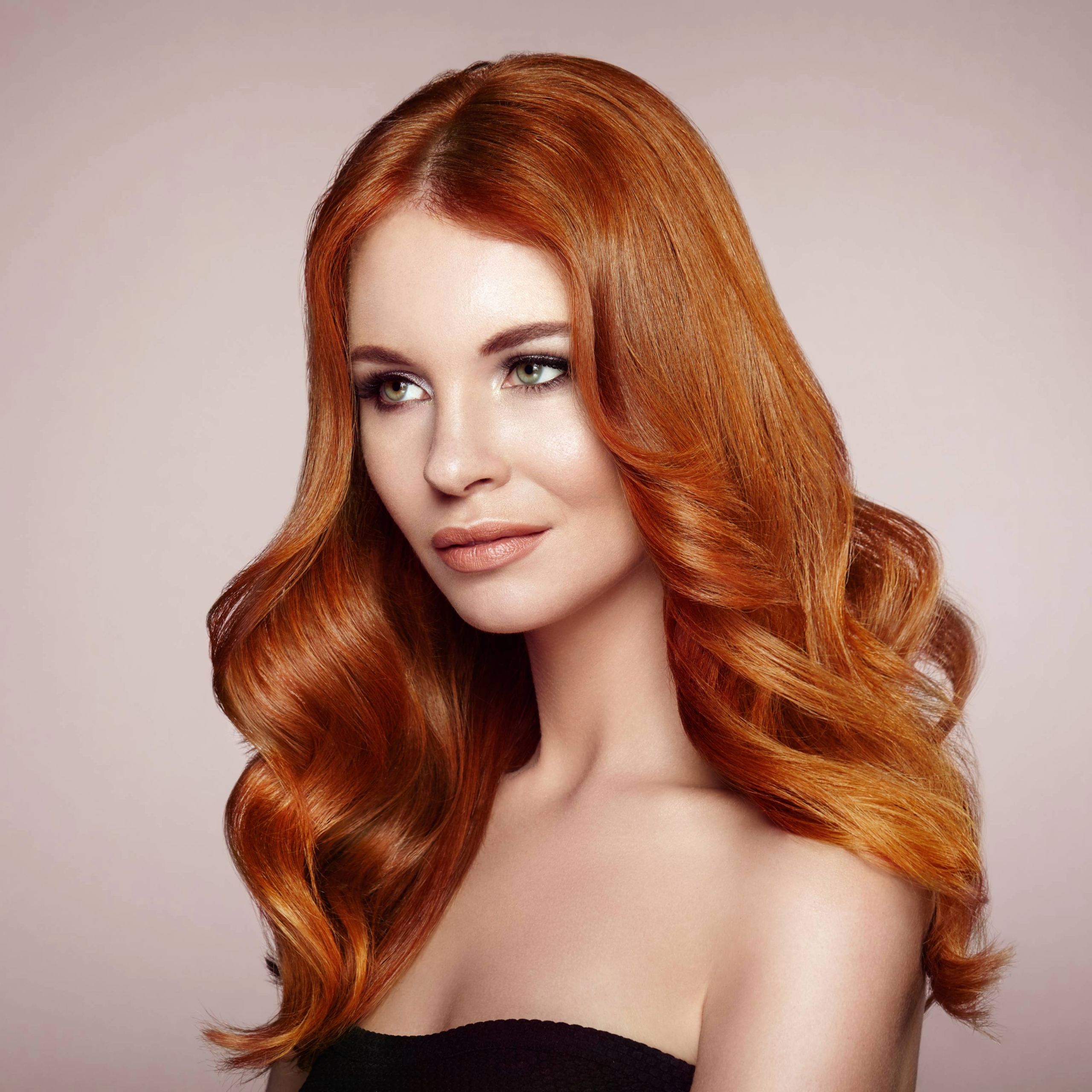 Chica cabello rojo ondulado posando de perfil.